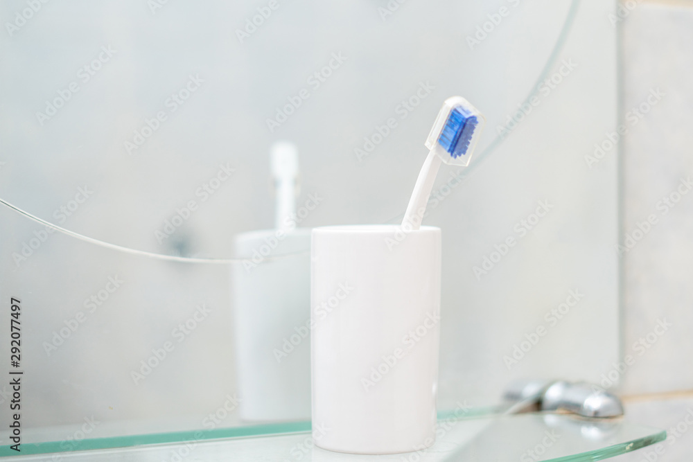 a single simple toothbrush in a glass in bathroom a single simple toothbrush in a glass in bathroom