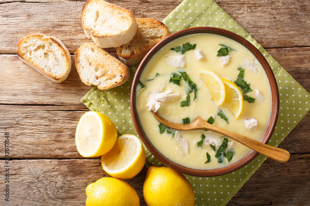 Hot greek lemon soup with chicken close-up in a bowl with bread. Horizontal top view Hot greek lemon soup with chicken close-up in a bowl with bread. Horizontal top view