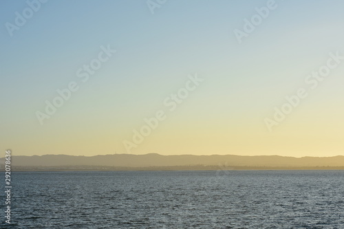 Cold morning in large harbor with distant landscape in background.