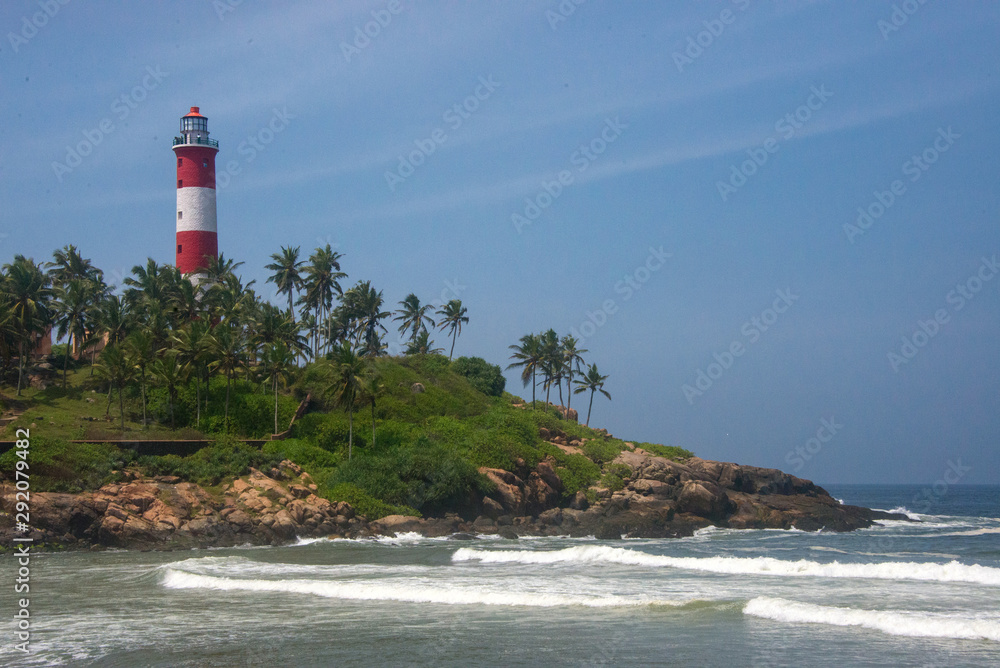 Lighthouse red and white tower and waves of the Arabian Sea in Kovalam, Kerala, India