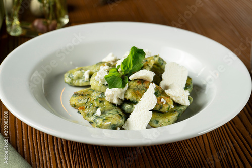 Green Gnocchi with basil, spinach, pesto feta cheese in composition with green cloth and olive oil. Close up, selective focus. Traditional italian cuisine.