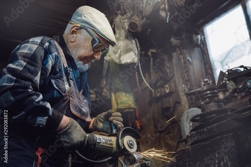 Senior elderly male turner handles metal on machine. Concept pension worker industrial, workplace
