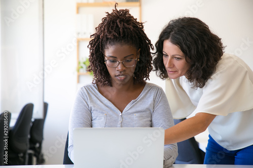 Принти на полотні Senior colleague helping newcomer with corporate software