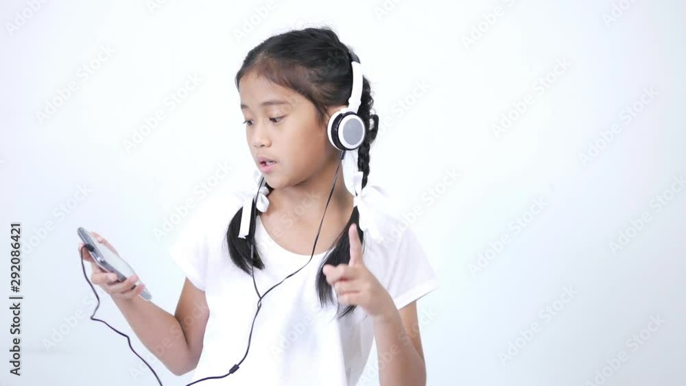 The girl looks cute and wears a white shirt and a braid tied with a white ribbon using the headphones, listening to music from social media on smartphone, singing softly and rocking along the song. The girl looks cute and wears a white shirt and a braid tied with a white ribbon using the headphones, listening to music from social media on smartphone, singing softly and rocking along the song.