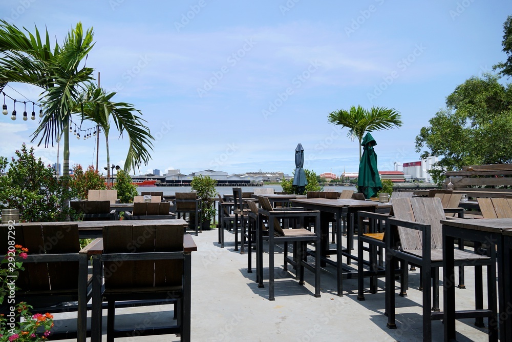 Fototapeta premium Luxury terrace balcony with dining wooden table and chairs and palm tree in a restaurant or resort, Outdoor area, Space for text in template