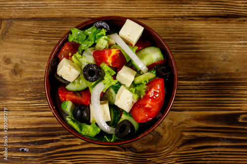 Greek salad with fresh vegetables  feta cheese and black olives on wooden table. Top view