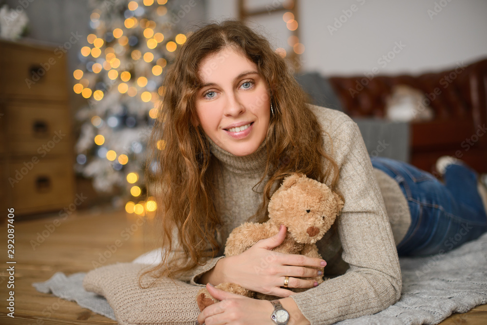 smiling woman with teddy bear and christmas tree indoors smiling woman with teddy bear and christmas tree indoors