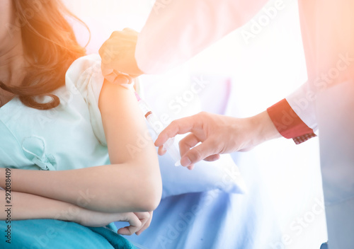Hospitalized woman lying in bed while doctor checking examining his pulse. Doctor giving a patient injection. Cropped image of handsome mature doctor. selective focus. have flare.