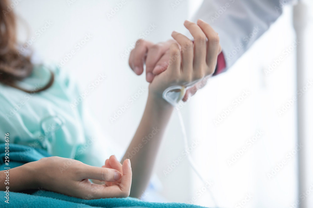 Hospitalized woman lying in bed while doctor checking examining his pulse. Doctor is checking patience's pulse by fingers, medical checking on bed. selective focus. Hospitalized woman lying in bed while doctor checking examining his pulse. Doctor is checking patience's pulse by fingers, medical checking on bed. selective focus.