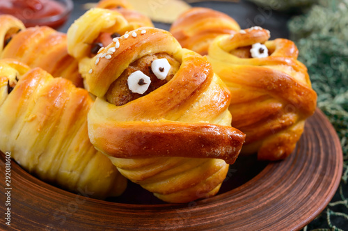 Funny sausage and cutlets mummies in dough with eyes, ketchup on table. Halloween food. Close up