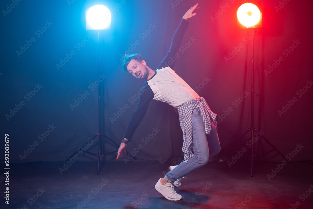 Dance, hip-hop and reggaeton concept - young man dancing over the lights.