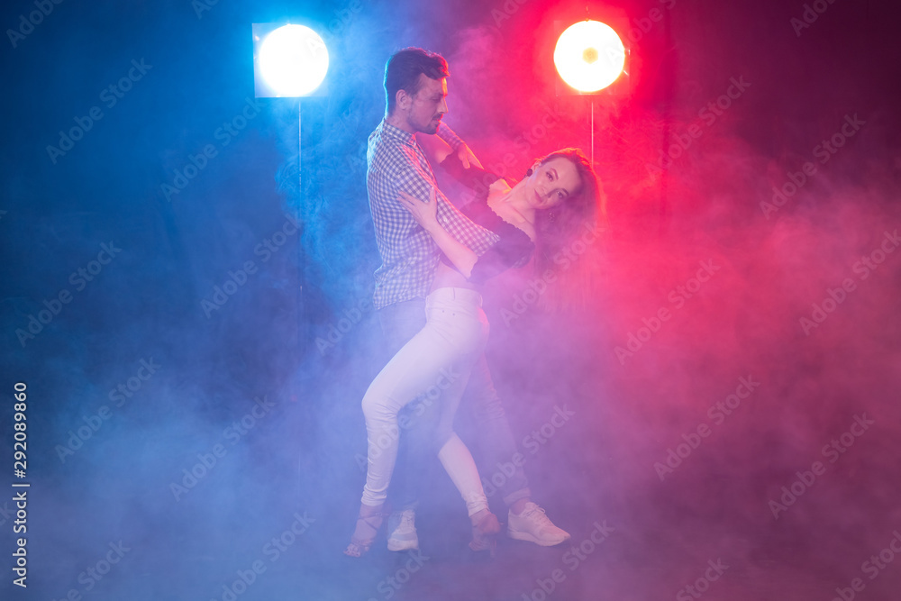 Social dance, bachata, salsa, kizomba, zouk and tango concept - Man hugs woman while dancing over lights