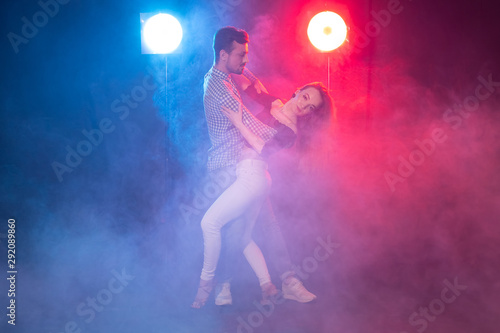 Social dance, bachata, salsa, kizomba, zouk and tango concept - Man hugs woman while dancing over lights