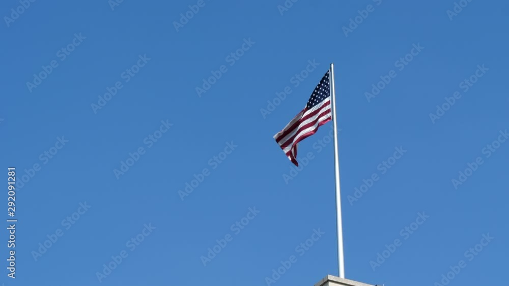 American Flag Waving On Wind On Top Of Building Under Blue Sky American Flag Waving On Wind On Top Of Building Under Blue Sky