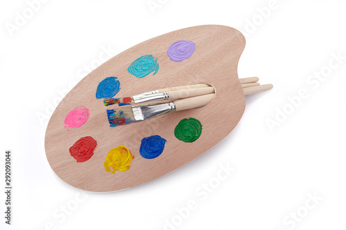 Wooden palette with paints and brushes isolated on white background