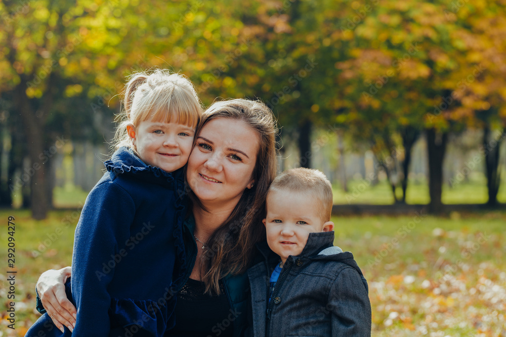 Beautiful young mother with daughter and son are walking in the autumn park. close-up portrait Beautiful young mother with daughter and son are walking in the autumn park. close-up portrait