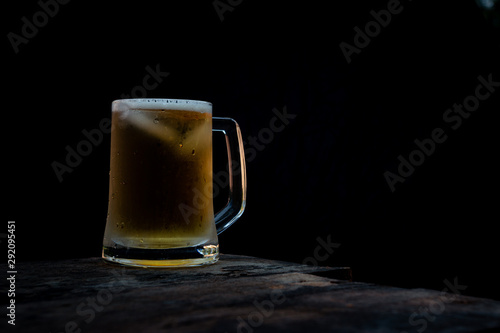 mug of beer with foam on dark background