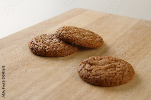 Three fresh baked oatmeal cookies at wooden board, shallow depth, selective focus