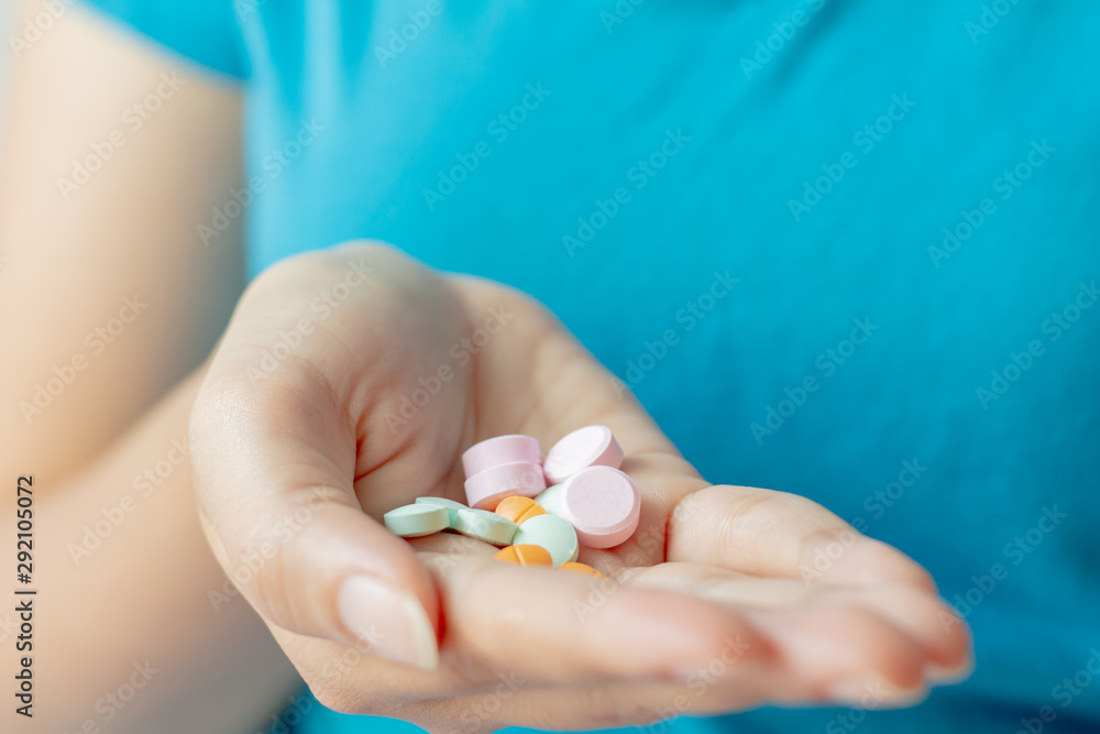 Woman with blue t-shirt holding pills on on hand. Woman with blue t-shirt holding pills on on hand.