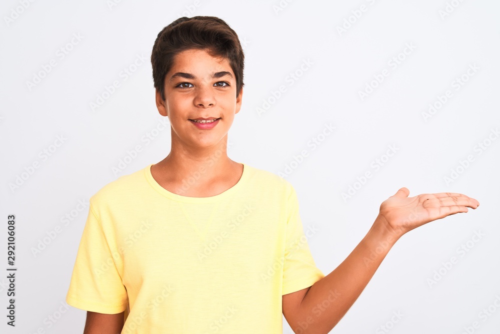 Handsome teenager boy standing over white isolated background smiling cheerful presenting and pointing with palm of hand looking at the camera. Handsome teenager boy standing over white isolated background smiling cheerful presenting and pointing with palm of hand looking at the camera.