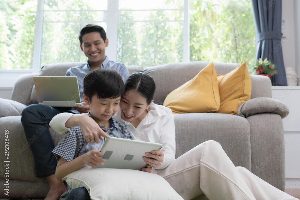 Asian family father, mother and son playing laptop computer together in living room, happy family concept Asian family father, mother and son playing laptop computer together in living room, happy family concept