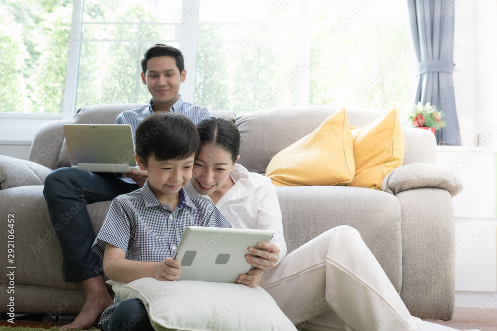 Asian family father, mother and son playing laptop computer together in living room, happy family concept Asian family father, mother and son playing laptop computer together in living room, happy family concept