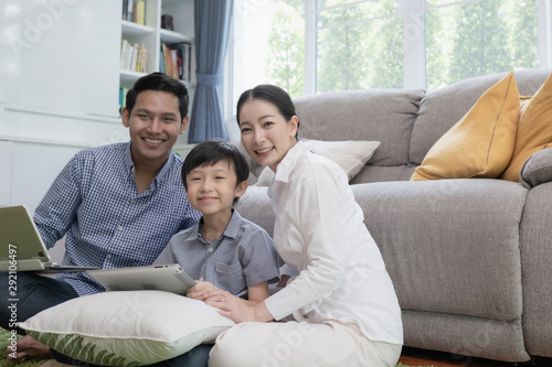 Asian family father, mother and son playing laptop computer together in living room, happy family concept