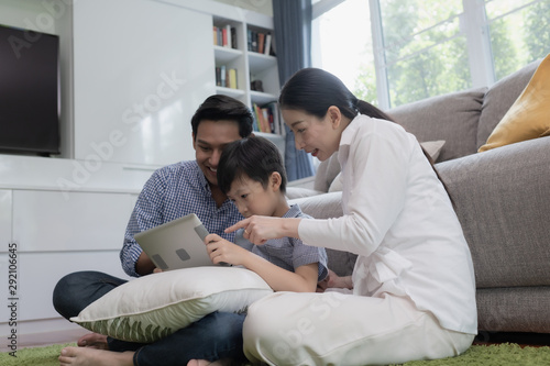 Asian family father, mother and son playing laptop computer together in living room, happy family concept