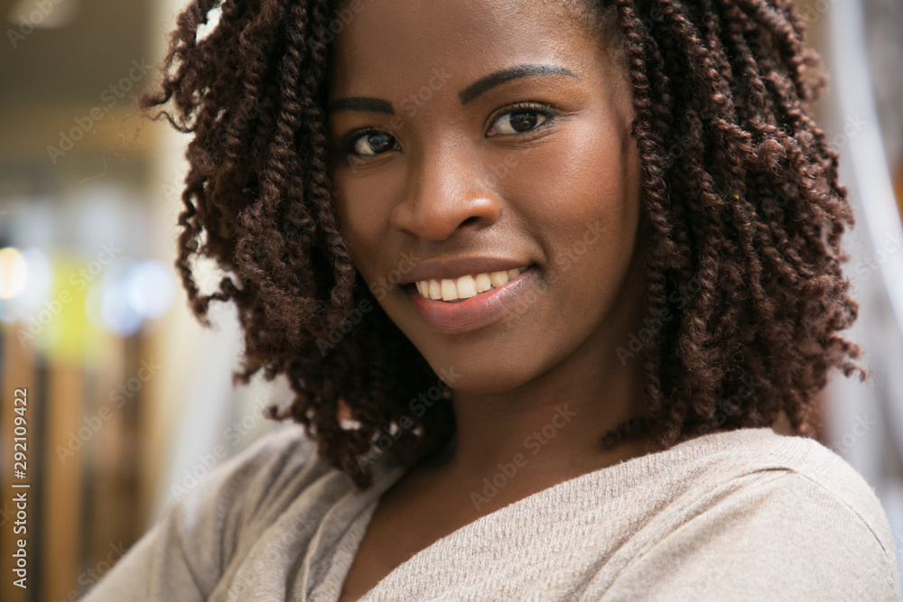 Closeup shot of smiling woman posing at public library. Front view of smiling lady with dreadlocks posing. Knowledge concept Closeup shot of smiling woman posing at public library. Front view of smiling lady with dreadlocks posing. Knowledge concept