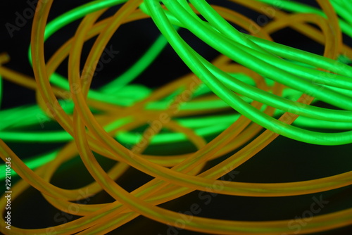 Bright luminous yellow and green  lime neon wires in different formats and layouts. An electroluminescent wire  a neon light guide  an ice tube are folded into different structures and shapes.