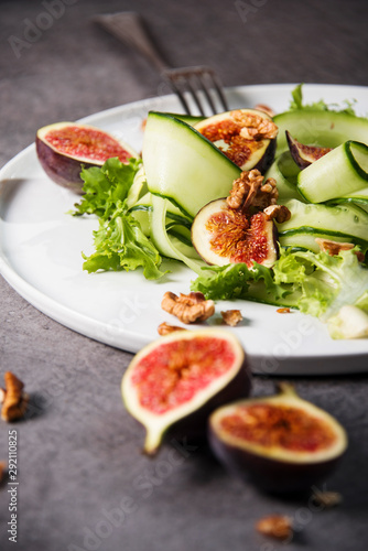 Green salad with figs on grey background. Gourmet conception.