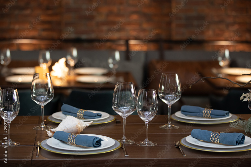 wooden table served with plates, forks, spoons, glasses, napkins in the restaurant wooden table served with plates, forks, spoons, glasses, napkins in the restaurant