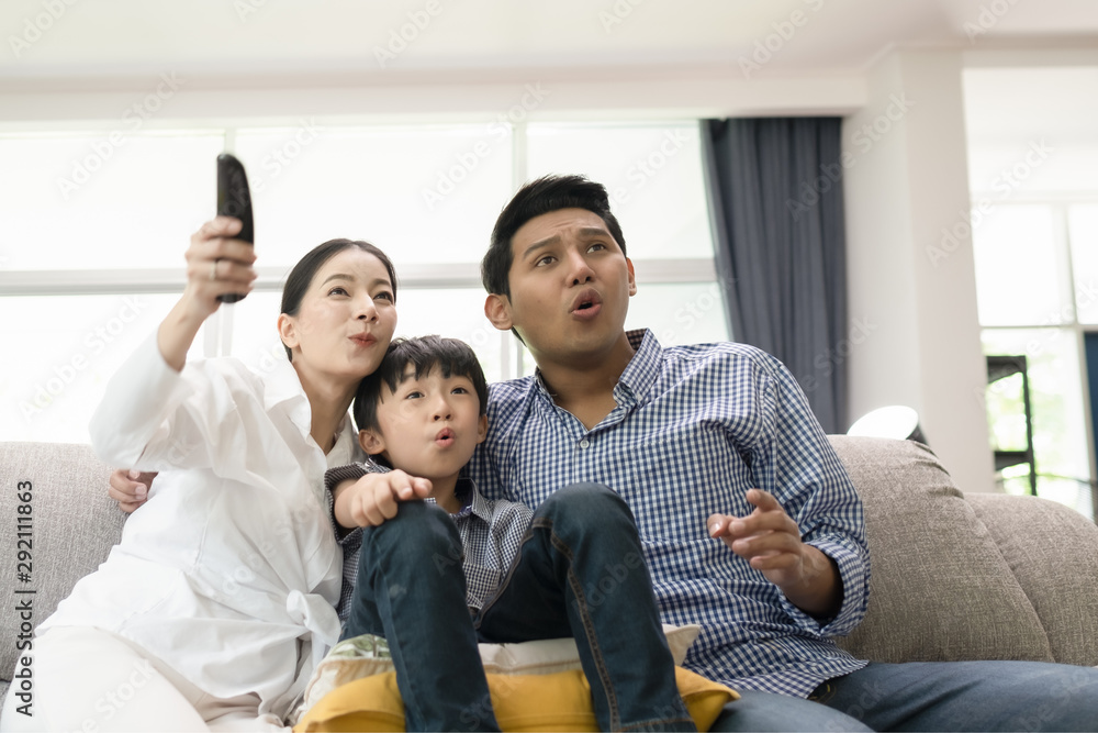 young family, father, mother and son watching TV feeling exciting together in living room, happy family concept young family, father, mother and son watching TV feeling exciting together in living room, happy family concept