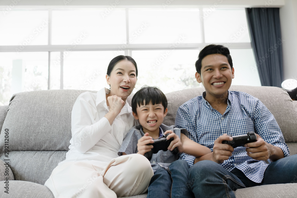 emotion of young family, father, mother and son watching TV and playing game together in living room, happy family concept emotion of young family, father, mother and son watching TV and playing game together in living room, happy family concept