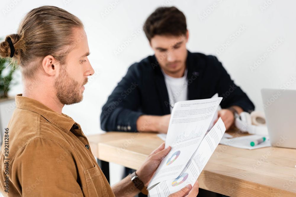 selective focus of handsome man in shirt doing paperwork in office selective focus of handsome man in shirt doing paperwork in office
