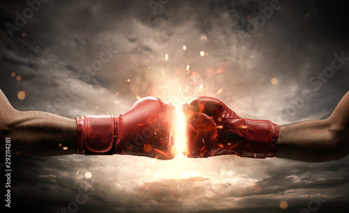 Boxing fight, close up of two fists hitting each other over dark, dramatic sky with copy space