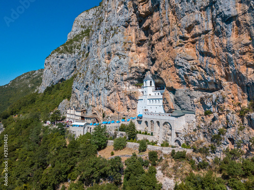 Aerial view of The Monastery of Ostrog, Serbian Orthodox Church situated against a vertical background, high up in the large rock of Ostroška Greda, Montenegro. Dedicated to Saint Basil of Ostrog  photo