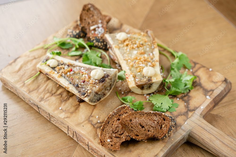 Beef bone marrow with chimichurri sauce and toasted bun. Served on a chopping wooden Board. Menu BBQ restaurant Beef bone marrow with chimichurri sauce and toasted bun. Served on a chopping wooden Board. Menu BBQ restaurant
