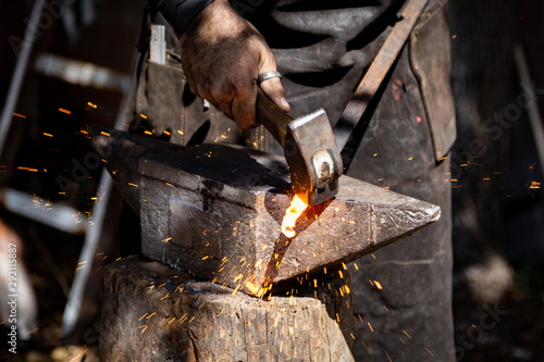 Fényképezés The blacksmith manually forging the molten metal on the anvil in smithy with spa