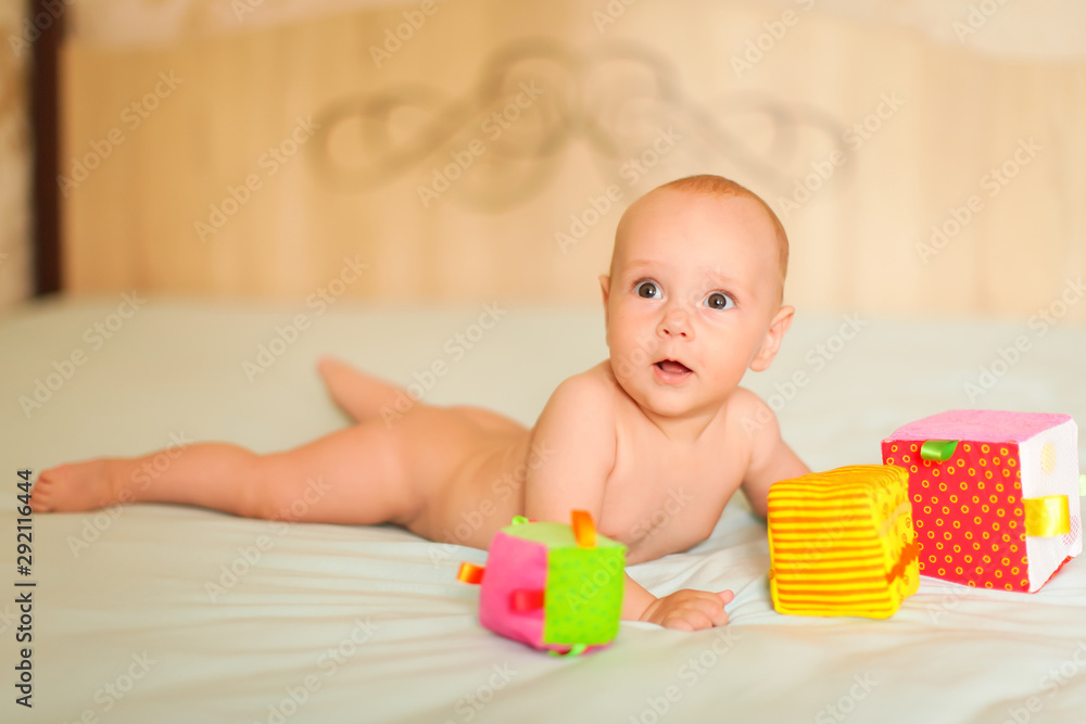 Portrait of little cute five month old caucasian baby lies on his stomach and plays with soft cubes in selective focus. Portrait of little cute five month old caucasian baby lies on his stomach and plays with soft cubes in selective focus.