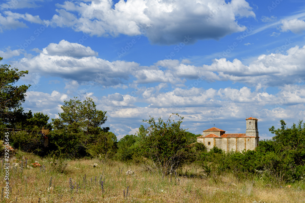 Vista de la ermita de La Blanca, entre vegetación y bajo un cielo azul con nubes, cerca de la población de Cabrejas del Pinar, en la provincia de Soria. Castilla León. España