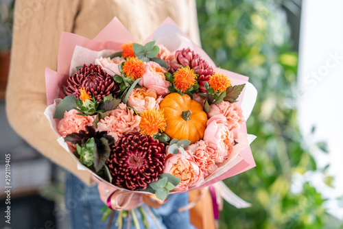 Autumn bouquet of mixed flowers in womans hands. The work of the florist at a flower shop. Fresh cut flower. photo