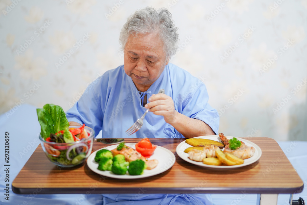Asian senior or elderly old lady woman patient eating breakfast healthy food with hope and happy while sitting and hungry on bed in hospital.. Asian senior or elderly old lady woman patient eating breakfast healthy food with hope and happy while sitting and hungry on bed in hospital..