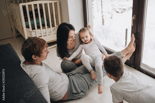 The family is sitting at the window and looking at the winter forest. Good New Year spirit. Morning in pajamas.