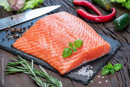 Fresh salmon fillet on black cutting board.