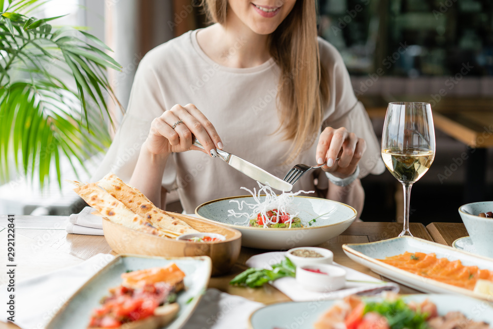 Portrait of a beautiful young elegant woman in the restaurant with a wine glass. Dinner and a variety of dishes on the table. Italian cuisine Portrait of a beautiful young elegant woman in the restaurant with a wine glass. Dinner and a variety of dishes on the table. Italian cuisine
