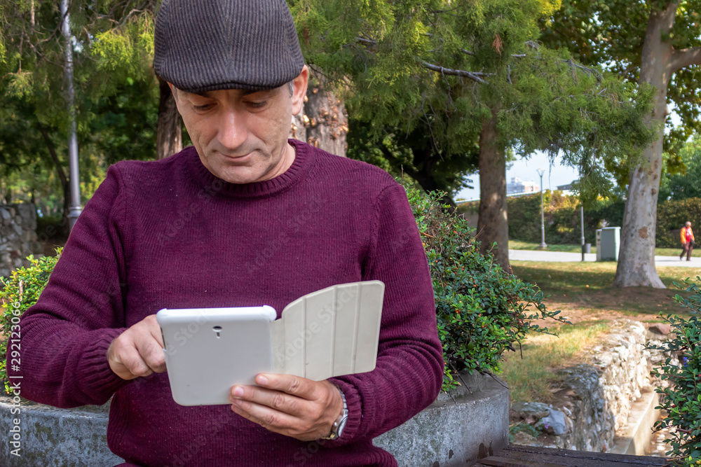 Fototapeta premium Middle Age Man Playing With Tablet in The Park