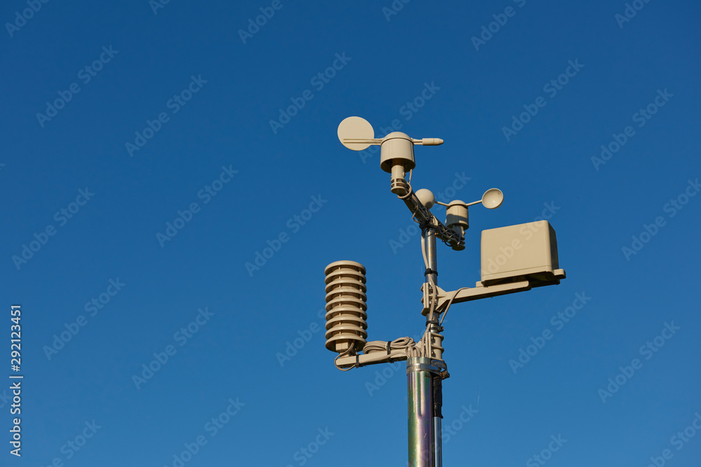 A small Amateur Weather Outdoor forecasting Station with rainfall gauge, thermometer, Anemometer and wind direction instruments on a metal pole. A small Amateur Weather Outdoor forecasting Station with rainfall gauge, thermometer, Anemometer and wind direction instruments on a metal pole.