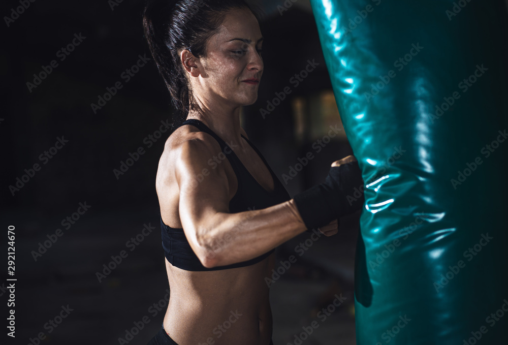 Female boxer punching a boxing bag in warehouse. Female boxer punching a boxing bag in warehouse.