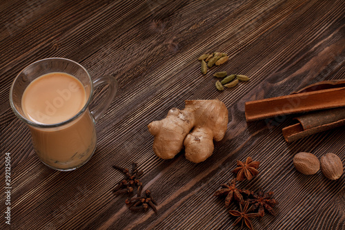 Masala tea ingridients and a cup of masala tea are on the brown wooden table